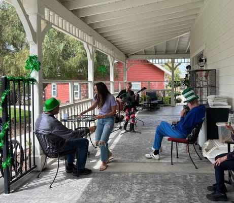 Residents enjoying music on a porch with a performer