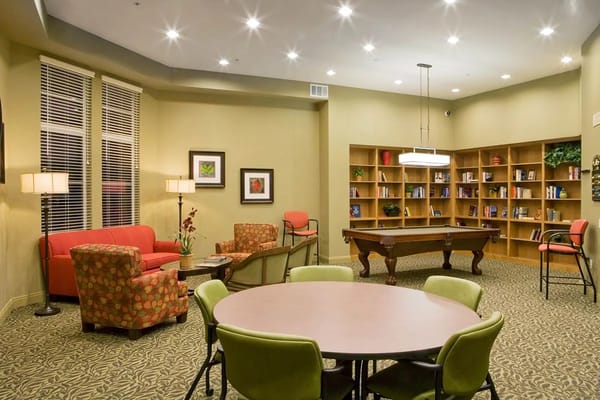 Cozy common area with seating, bookshelf, and pool table.