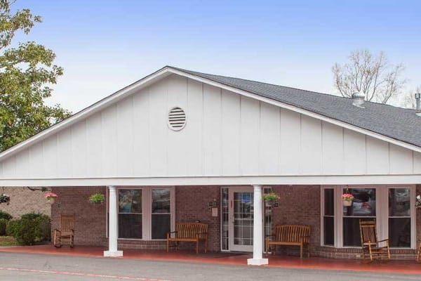 Front entrance of Magnolia Ridge Assisted Living Facility with wooden benches and floral decorations.