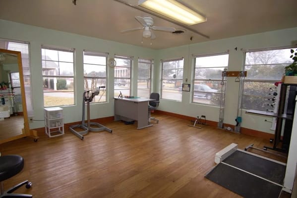 Bright therapy room with exercise equipment and windows