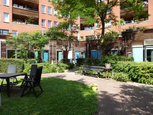 Spacious courtyard with benches and greenery at Marcantilaan Begeleid Wonen.
