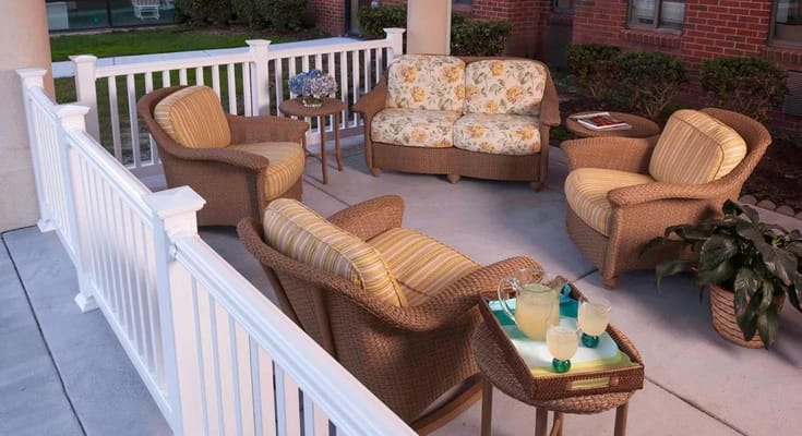 Comfortable wicker furniture on a patio with a floral couch and drinks
