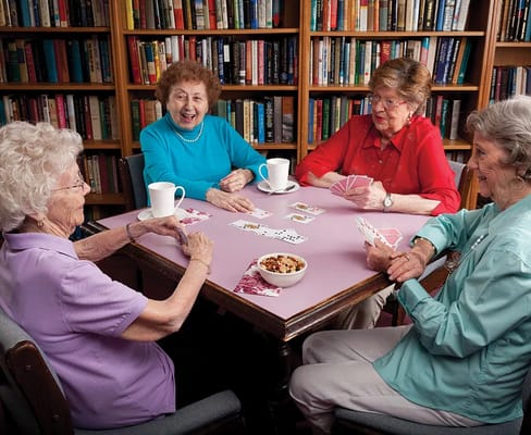 Four senior residents playing cards at a table