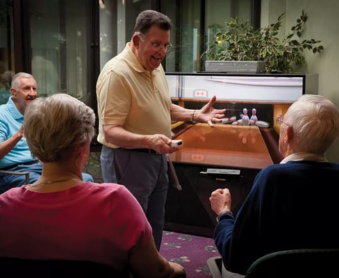 Residents enjoying a bowling simulation activity with a facilitator.