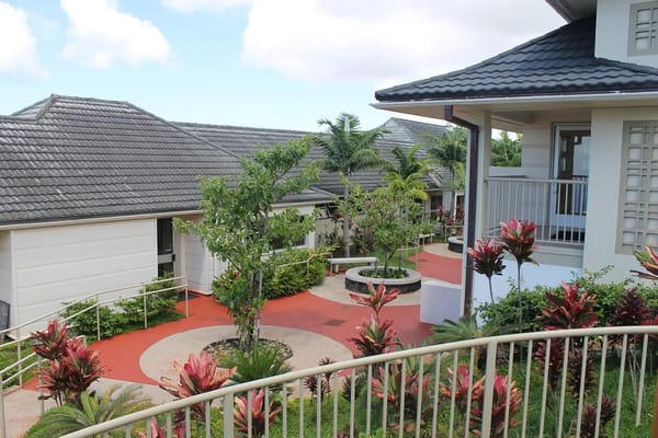 View of the courtyard with lush plants and pathways at Maunalani Nursing and Rehabilitation Center.