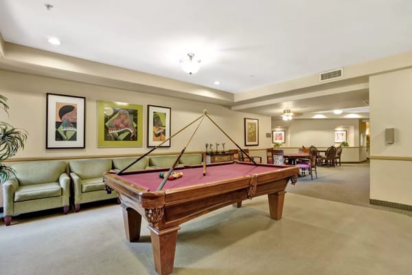 Billiards table in the game room with green seating and artwork.