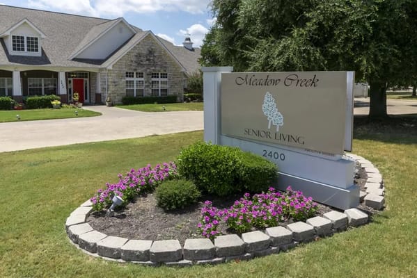 Sign for Meadow Creek Senior Living with flower bed.