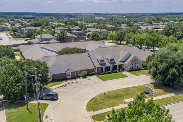 Aerial view of Meadow Creek Senior Living facility surrounded by residential area and greenery.