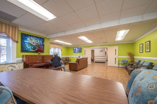 Resident playing piano in a vibrant common area