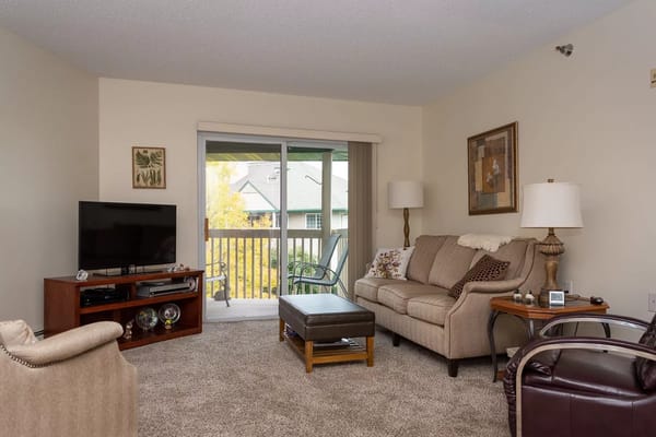 A cozy living room with a sofa, TV, and balcony access.