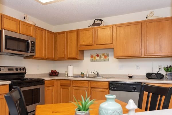 A modern kitchen featuring wooden cabinets, a microwave, and a dining table.