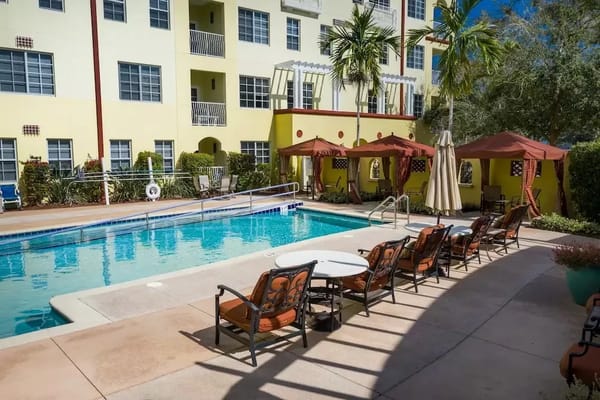Outdoor pool area with seating and cabanas