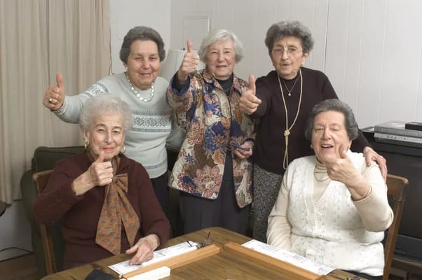 Five senior women smiling and giving thumbs up