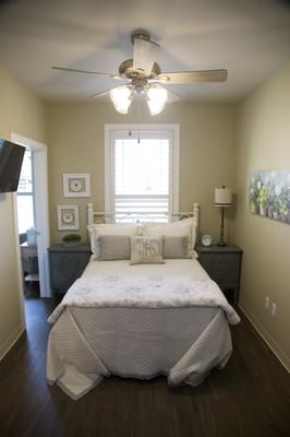 Cozy bedroom setup with light colors and a ceiling fan