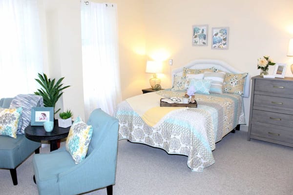 A well-decorated bedroom featuring a bed, seating area, and decorative elements.