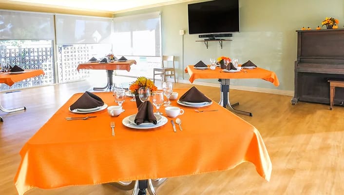 Brightly decorated dining area with orange tables set for a meal