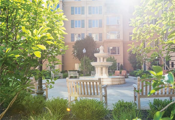 Courtyard featuring a fountain surrounded by benches and greenery