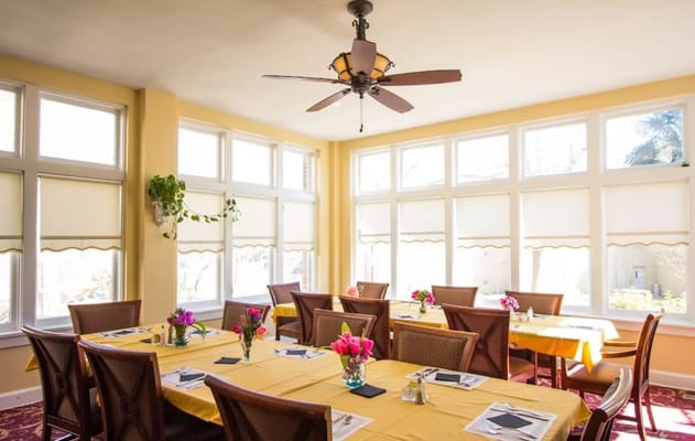 Bright dining room with yellow tables and floral centerpieces