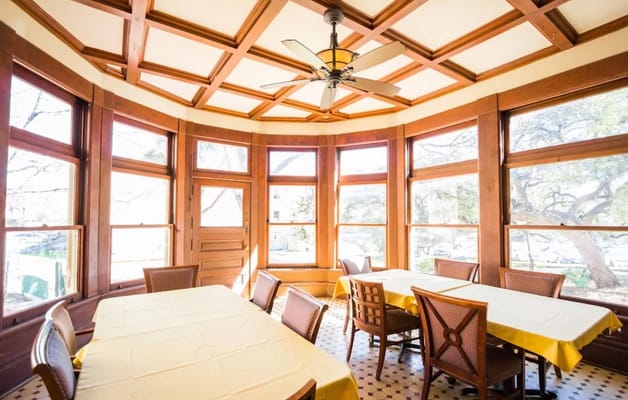 Bright dining room with wooden details and tables set with yellow tablecloths
