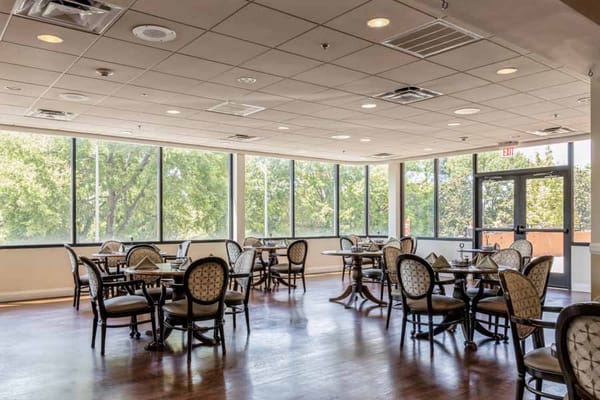 Bright dining area with tables and chairs, surrounded by large windows