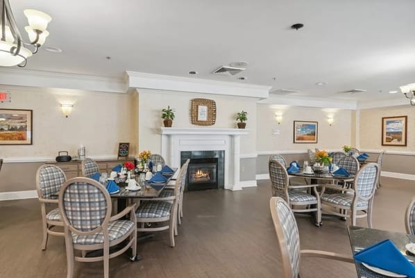 Cozy dining room with tables set for meals and a fireplace