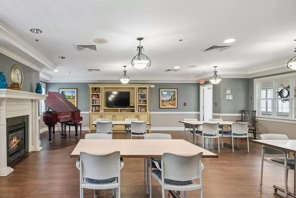 Spacious common room with tables, chairs, and a piano