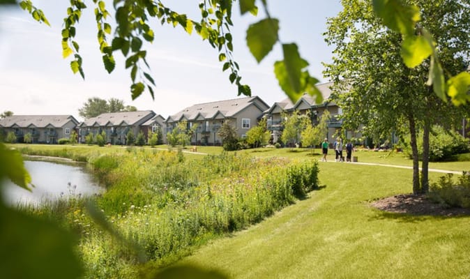 Residents walking along a path by a pond in the facility's garden