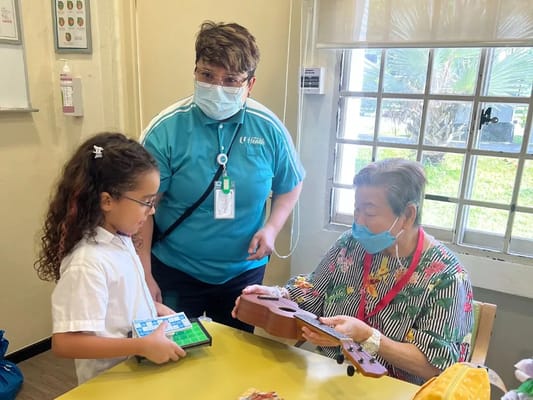 Staff member assisting a resident with a ukulele