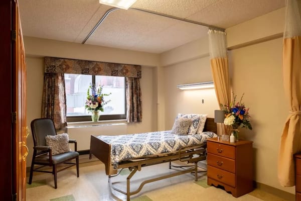 Private resident room with a hospital bed and flowers