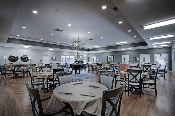 Spacious dining area with round tables and a grand piano