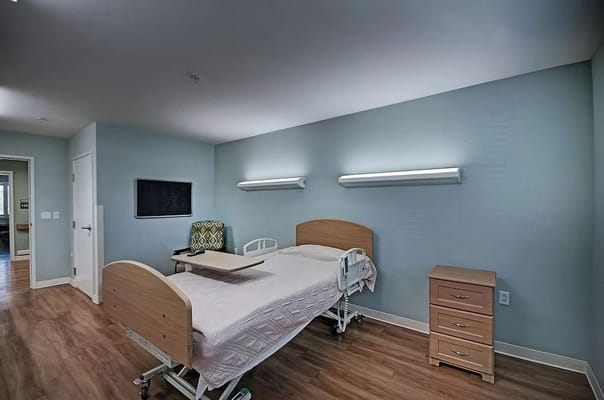 Patient room featuring a hospital bed, nightstand, and seating area