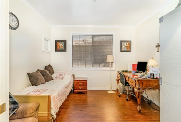 A cozy bedroom with a bed, desk, and natural light.
