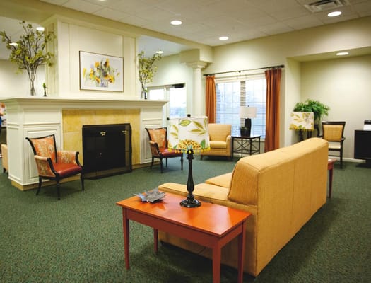 Living room with a fireplace, orange curtains, and comfortable seating at Nye Legacy.