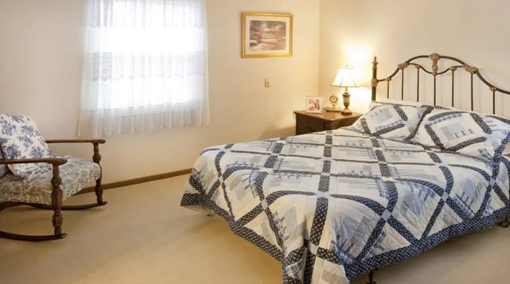 Comfortable bedroom with a bed, rocking chair, and lamp