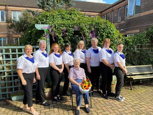 Staff members and a resident posing in a garden area