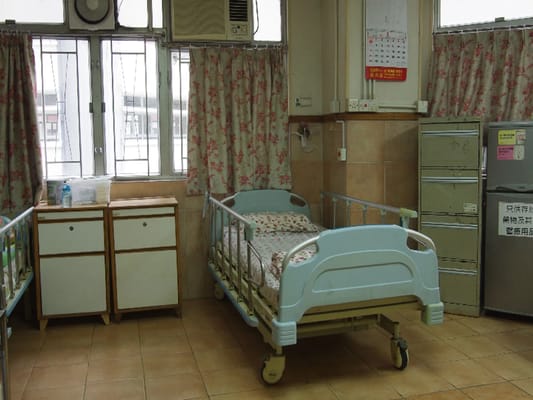 A bedroom with two hospital beds and wooden cabinets.