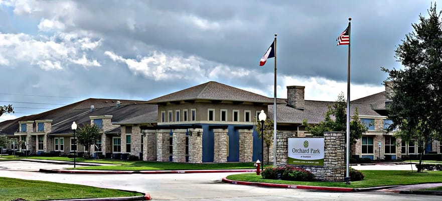 Front entrance of Orchard Park at Southfork with flags and sign