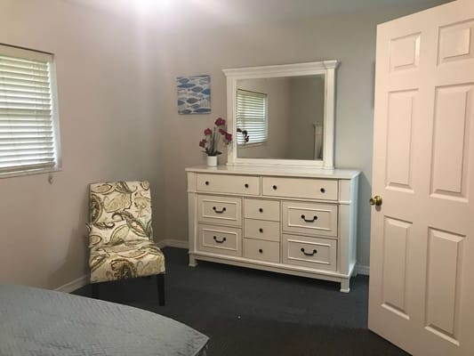 A well-furnished resident room with a dresser and mirror