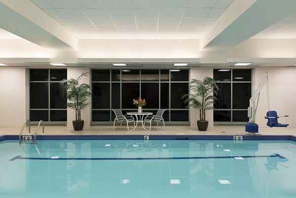 Indoor swimming pool area with lounge chairs and plants
