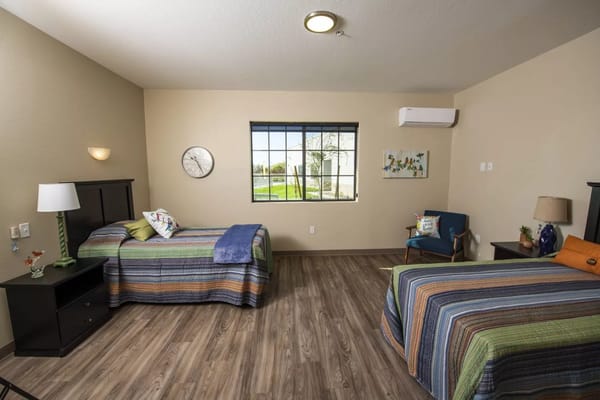 A shared resident room with two beds and seating area