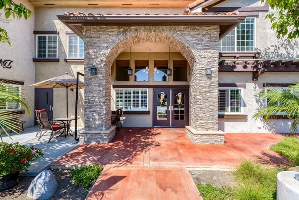 Entrance of Pacifica Senior Living South Coast with stone arch and outdoor seating