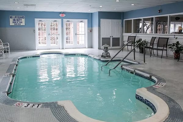Indoor swimming pool with stairs and seating area