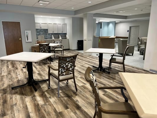 A spacious common area with tables and chairs in Papillion Manor.