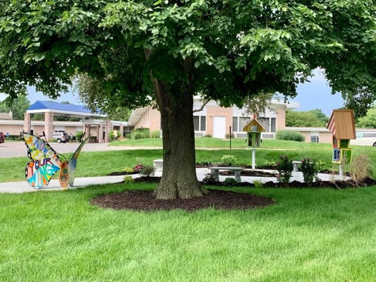 Colorful butterfly sculpture and small birdhouses in garden