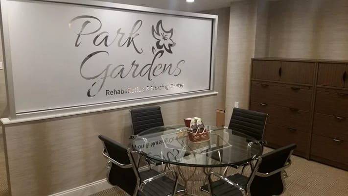 A modern meeting room featuring a glass table and a signature wall.