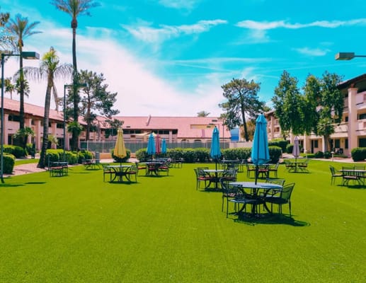 Green courtyard with tables and umbrellas at Park Terrace Senior Living