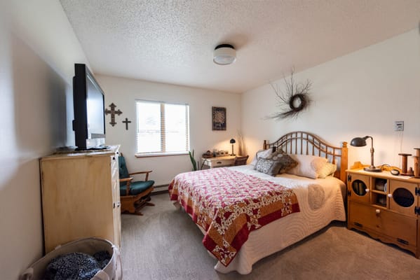 A well-decorated bedroom with a bed, TV, and window, showcasing a comfortable living space.