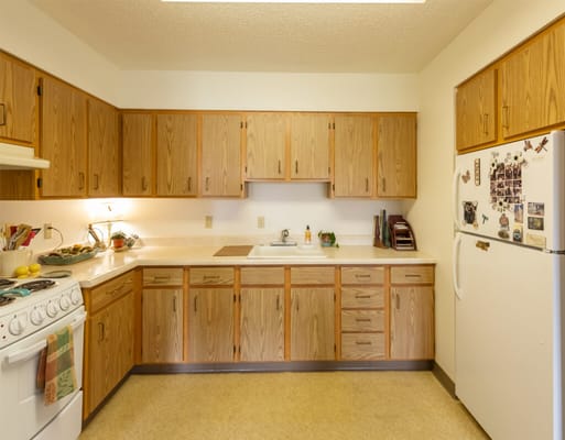 A spacious kitchen with wooden cabinets and white appliances