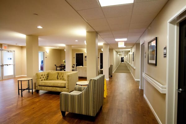 Spacious common area with seating and hallway at Patterson Pointe Senior Residence