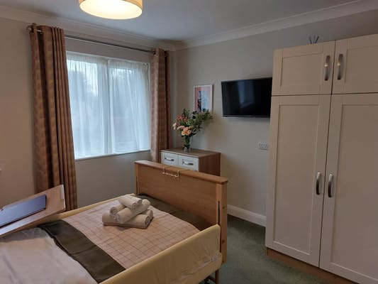 A well-furnished private resident room with a bed and flowers